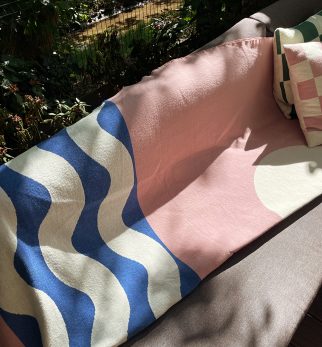 Designerska bawełniana narzuta na łóżko Surfer Baltic Blue od Hogai. 165x210 cm – różowo granatowy wzór inspirowany Bałtykiem. Aranżacja z poduszkami Hogai Chess.